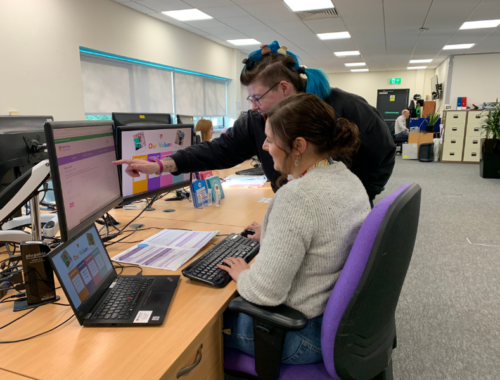 A staff member helping a colleague on the computer