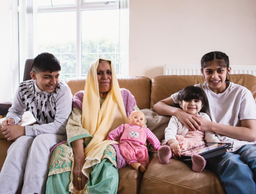 a mum and her three children sitting on a sofa smiling at the camera